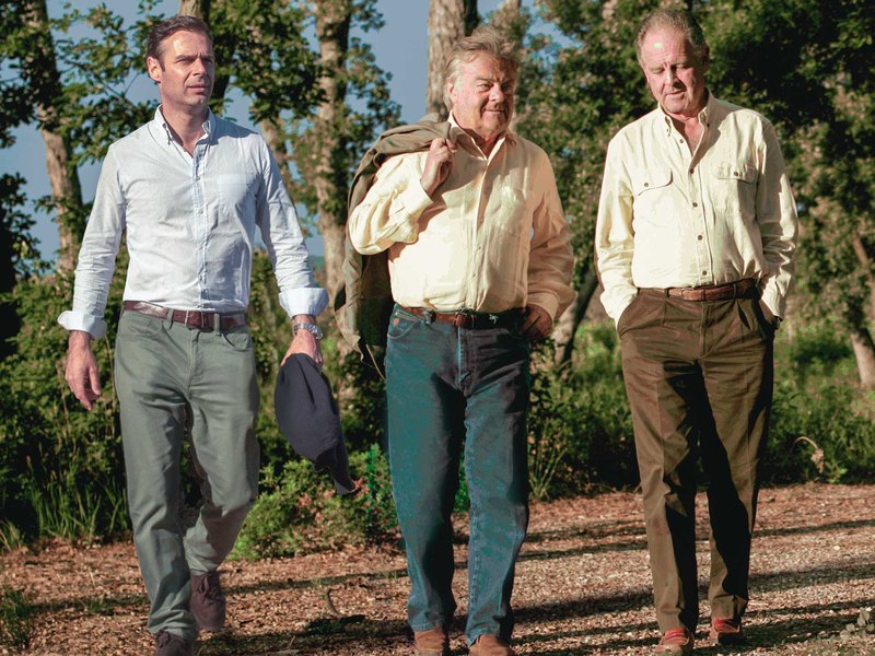 Tres hombres caminan por un sendero entre los viñedos de Biserno